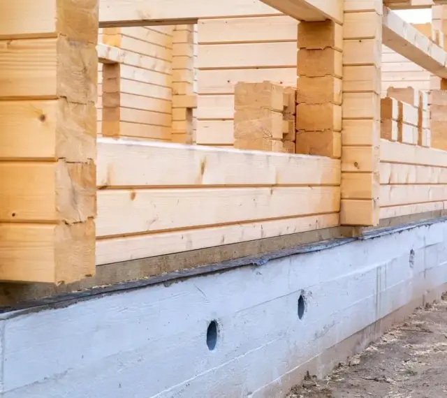 Budowa domu z bali w 2025 roku. Fundament i ściany z drewna w trakcie wznoszenia.