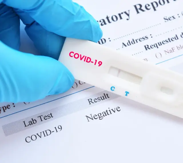 Rękawiczka w niebieskiej rękawiczce trzyma test na COVID-19 z negatywnym wynikiem. Zastanawiasz się, ile kosztuje test na covid?