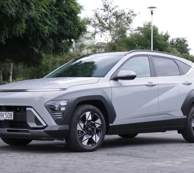 Szary Hyundai Kona Hybrid stoi na zewnątrz, z widocznym przodem i bokiem.