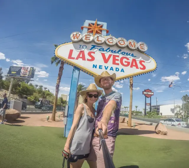 Para co przywieźć ze Stanów? Pamiątkę z Las Vegas! Uśmiechnięta para pozuje do selfie pod słynnym znakiem.