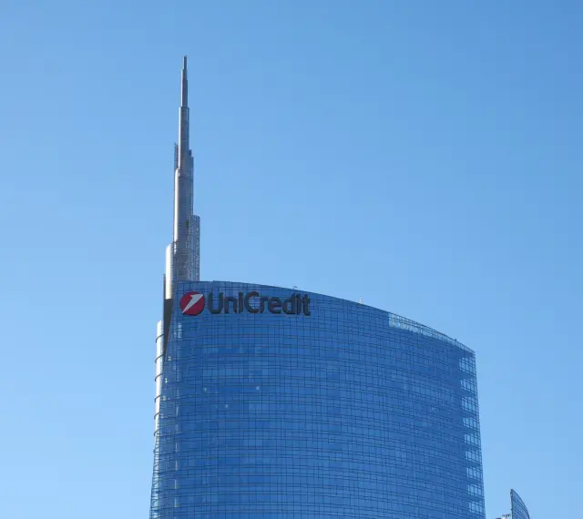 Szklany wieżowiec UniCredit z charakterystycznym logo, sięgający ku błękitnemu niebu. To symbol nowoczesności, jakby z przyszłości, niczym z wizji Aion Bank.
