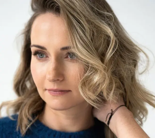 Zuzanna Irena Grabowska z burzą blond włosów i niebieskimi oczami, w granatowym swetrze.