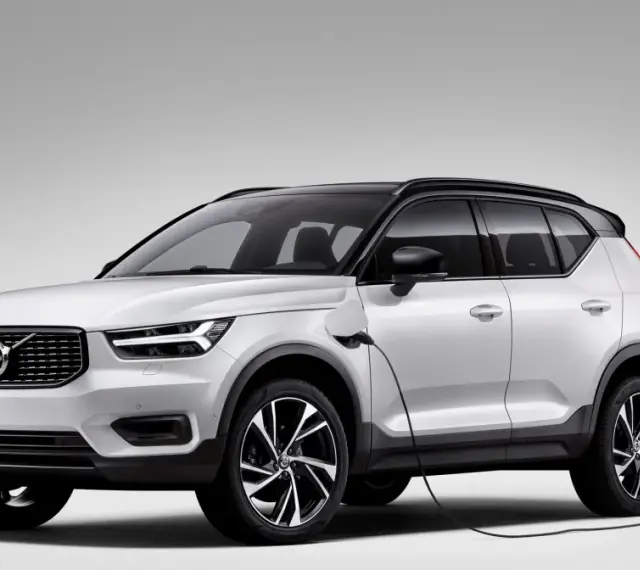 Biały Volvo XC40 Recharge plug-in hybrid podłączony do ładowarki.