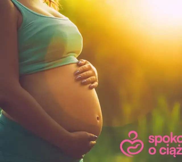 Brzuszek w 3 miesiącu ciąży, otulony ciepłym światłem. Ręce delikatnie go obejmują, symbolizując troskę i miłość.