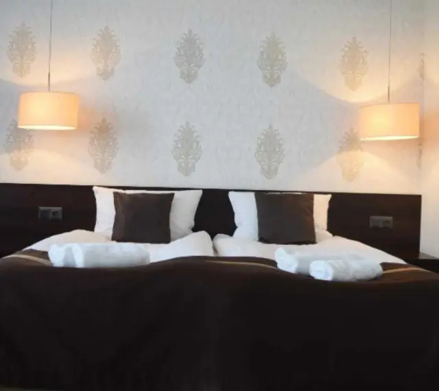Przytulny pokój hotelowy z podwójnym łóżkiem, białymi ręcznikami i lampami. Czy można wynająć pokój w hotelu mając 17 lat?
