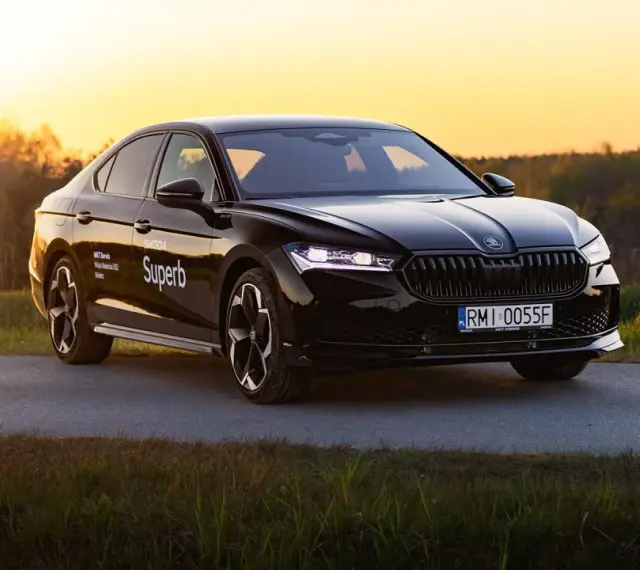 Czarny Skoda Superb 4 na tle zachodzącego słońca. Elegancki sedan z nowoczesnymi światłami i felgami.