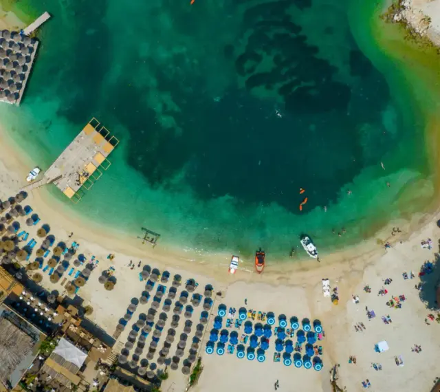 Widok z lotu ptaka na **Albania plaże** z turkusową wodą, leżakami i parasolami.