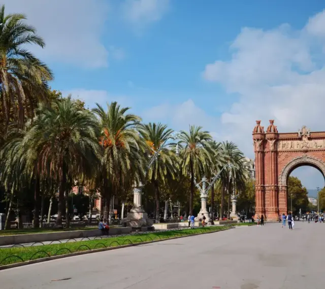 Łuk Triumfalny w Barcelonie, z rzędem palm i błękitnym niebem, to ikoniczne miejsce, które podkreśla wspaniałe barcelona położenie.