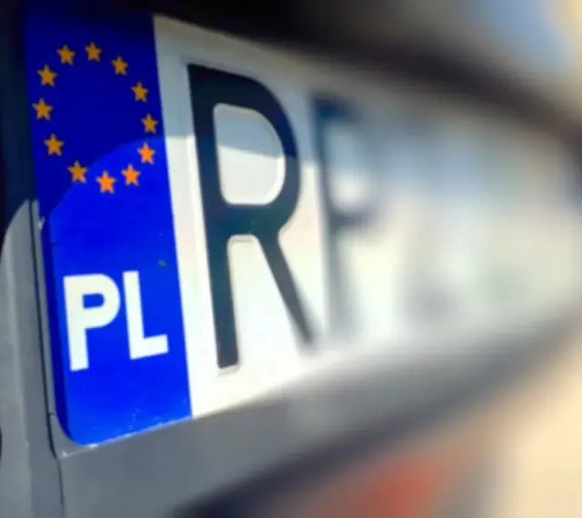 Zbliżenie na polską tablicę rejestracyjną z symbolem UE. Litery "PL" i fragment numeru rejestracyjnego są wyraźne.