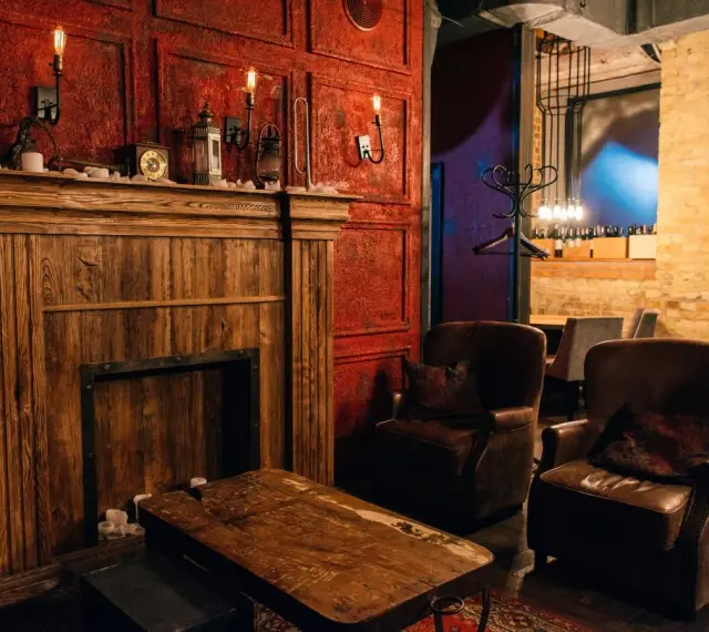 Drewniany kominek, skórzane fotele i lampy tworzą atmosferę **steampunk**.
