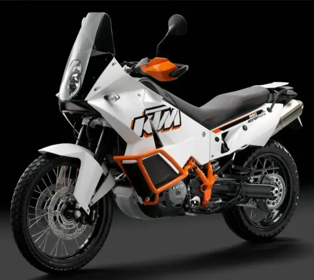 Biały motocykl KTM 990 Adventure z pomarańczowymi akcentami, gotowy na każdą przygodę.