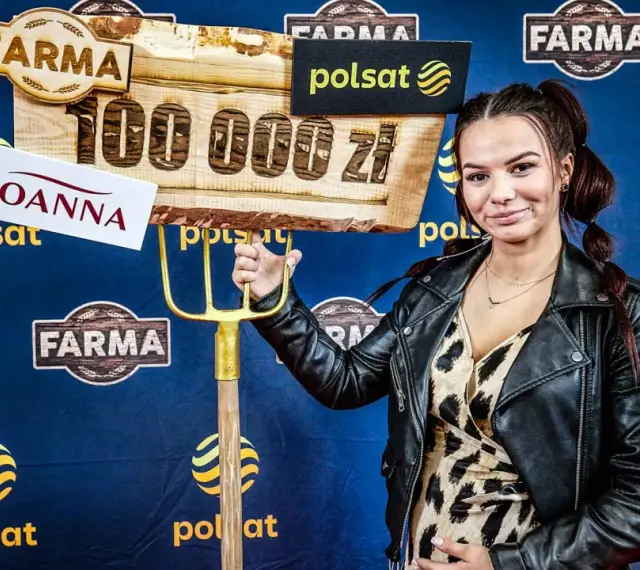 Joanna z "Farmy" trzyma widły i tablicę z napisem "100 000 zł".