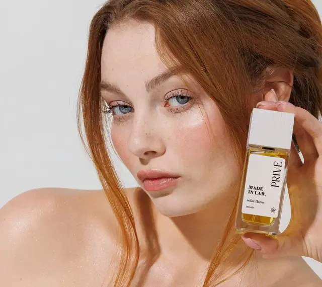 Ruda kobieta z niebieskimi oczami prezentuje perfumy "Made in Lab". Opinie o nich są zachęcające.