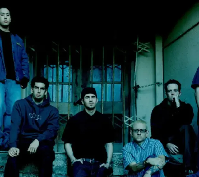 Sześciu członków zespołu Linkin Park, w tym Chester Bennington, pozuje na schodach.