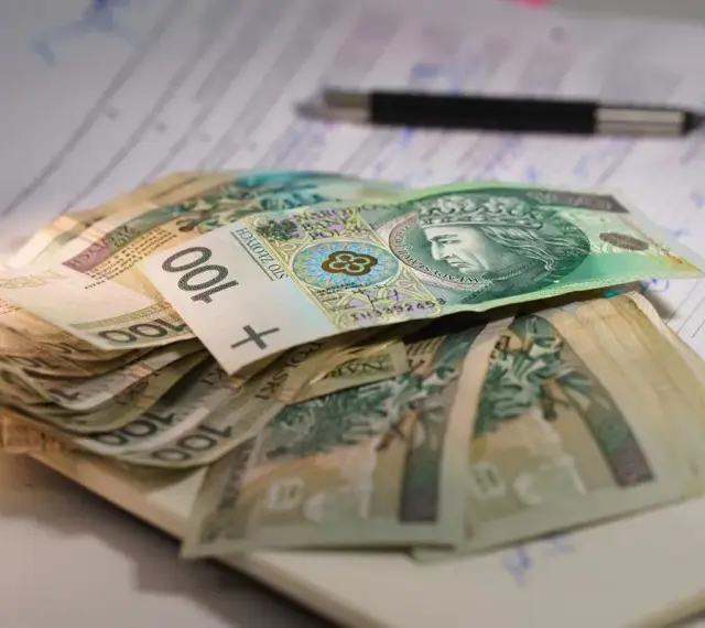 Stos banknotów 100 zł na dokumentach. Czy to wystarczy na najniższą emeryturę?
