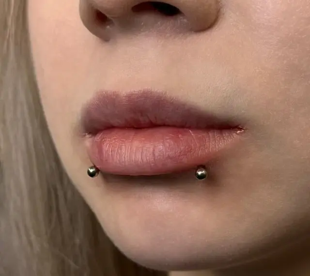 Cyber bites piercing na ustach, podkreślający ich kształt.