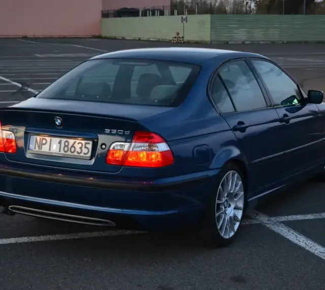 Niebieskie BMW E46 330d na parkingu. Wiele osób chwali ten model za osiągi i komfort.