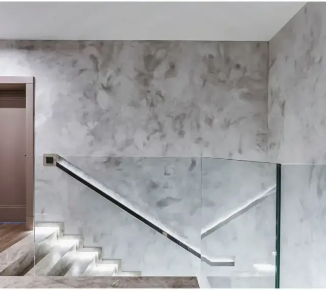 Nowoczesny hol z podświetlanymi schodami i szklaną balustradą. Efektowny tynk na ścianie dodaje wnętrzu elegancji.