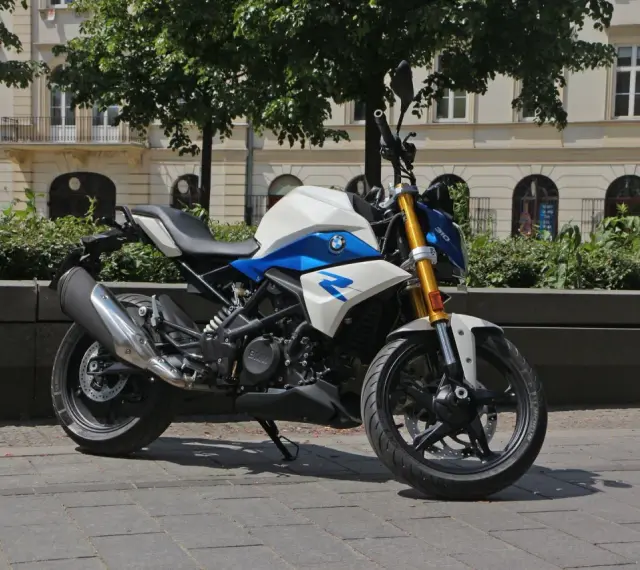 Biało-niebieski motocykl BMW G 310 R na tle kamienicy. Sprawdź jego dane techniczne!