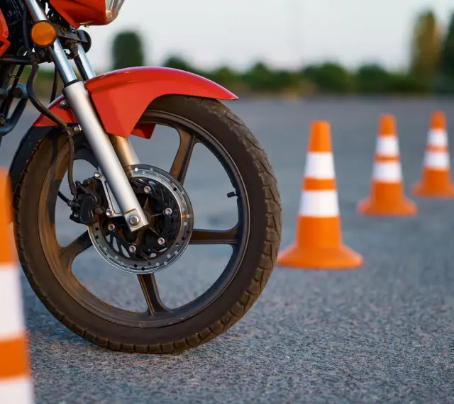 Czerwony motocykl i pomarańczowe pachołki na placu manewrowym. Przygotowanie do egzaminu na kategorie prawa jazdy na motor.