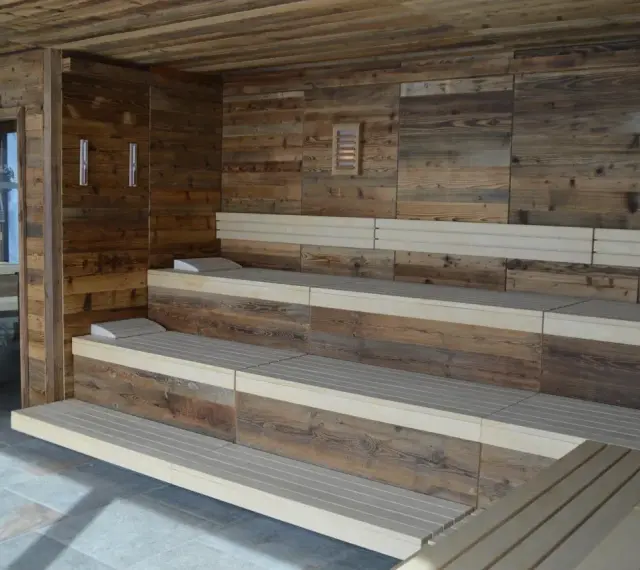 Drewniana sauna w domu z wielopoziomowymi ławami i kamienną podłogą. Idealne miejsce na relaks.