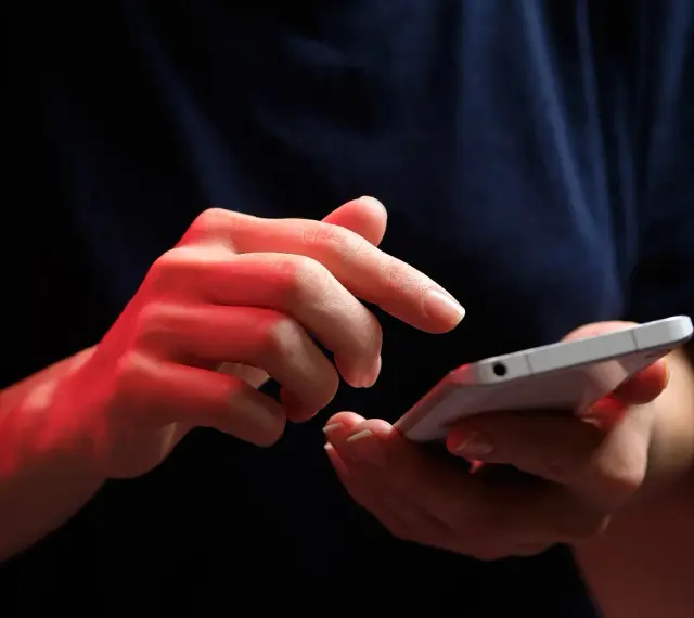 Dłonie z czerwonym podświetleniem obsługują smartfon, być może ustawiając **direct debit** na rachunki.