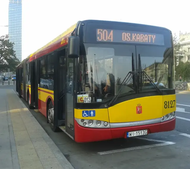 Autobus 504 OS.KABATY z numerem bocznym 8127 stoi na przystanku. W tle widać nowoczesne budynki.