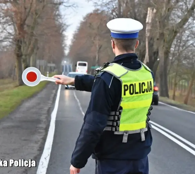 Policjant w kamizelce odblaskowej zatrzymuje ruch, by sprawdzić, ile promili ma kierowca.