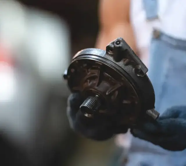 Mechanik trzyma element serwa hamulcowego. Objawy awarii mogą być różne, np. twardy pedał hamulca.