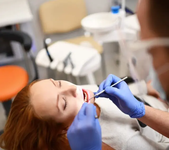 Pacjentka z rudymi włosami u dentysty. Badanie jamy ustnej, które może być związane z diagnostyką twardziny układowej.