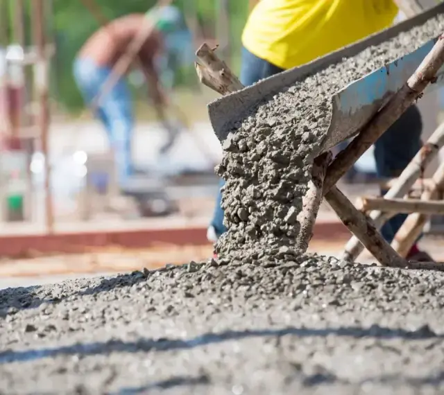 Betoniarka wylewa świeży beton. Zastanawiasz się, ile cementu na kubik betonu? Budowa trwa.