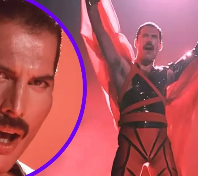 Freddie Mercury w czerwonym stroju, z rękami w górze, promuje swój **freddie mercury solo album**. Obok jego twarz z charakterystycznym wąsem.