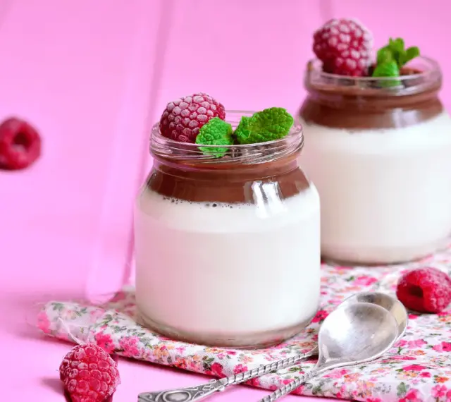 Två glas med choklad- och vaniljpannacotta, toppade med hallon och mynta. Perfekt som dessertvin till pannacotta.