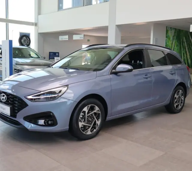 Niebieski Hyundai i30 Wagon z 2015 roku stoi w salonie samochodowym.