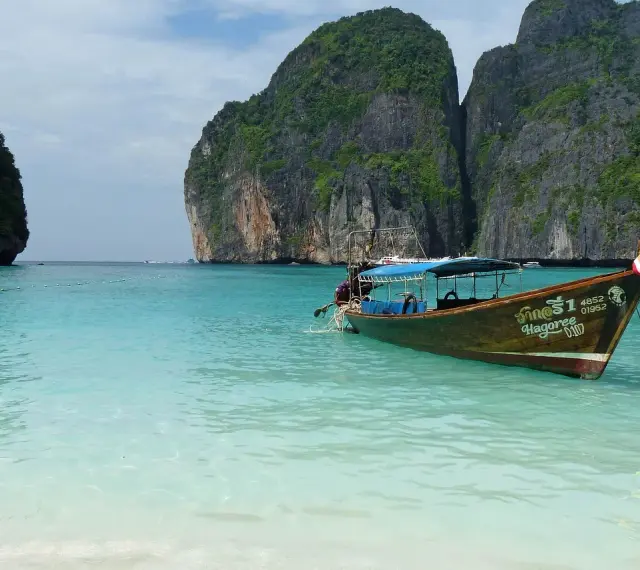 Łódź kołysze się na turkusowych wodach Maya Bay, otoczonej majestatycznymi klifami.