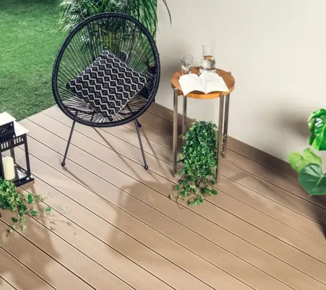 Drewno kompozytowe to świetny pomysł, czym wyłożyć balkon. Wygodne krzesło, stolik i rośliny tworzą przytulną przestrzeń.