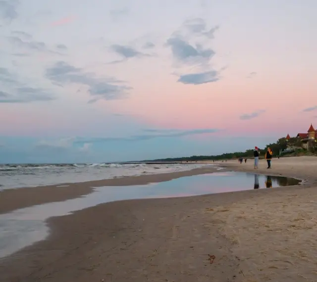 Zachód słońca nad morzem w kurorcie niedaleko Lęborka. Piękne, pastelowe niebo odbija się w wodzie na plaży.