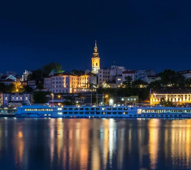 Nocny Belgrad z rzeką i statkiem wycieczkowym. Czy do Serbii potrzebny jest paszport? Sprawdź przed podróżą!