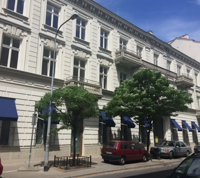 Kamienica z balkonami i niebieskimi markizami. Zastanawiasz się, dlaczego koszt czynszu w blokach z 2026 roku jest wyższy niż w kamienicach?