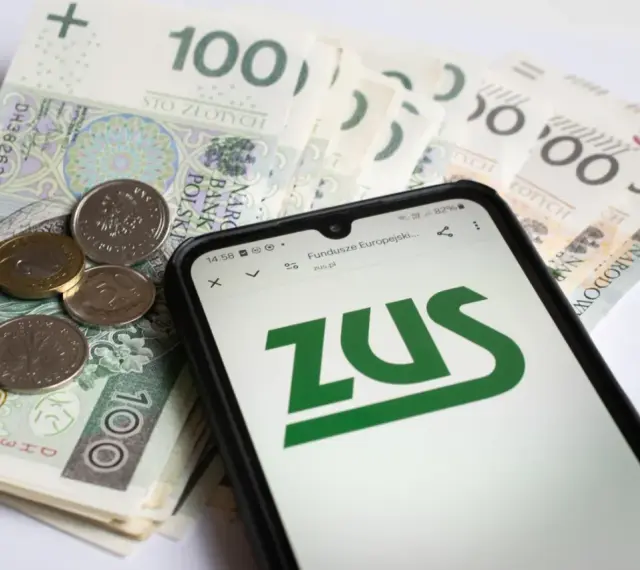 Złotówki i monety obok telefonu z logo ZUS. Może to być związane z wnioskiem o zasiłek opiekuńczy.