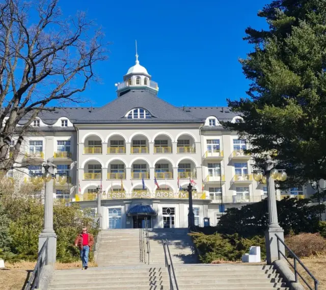 Piękny budynek sanatorium w Jeseniku, z charakterystycznymi arkadami i żółtymi balustradami. To jedna z głównych atrakcji regionu.