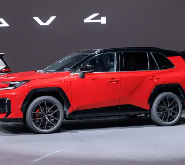 Czerwony, tani SUV z czarnym dachem i felgami, prezentowany na wystawie obok białego modelu.