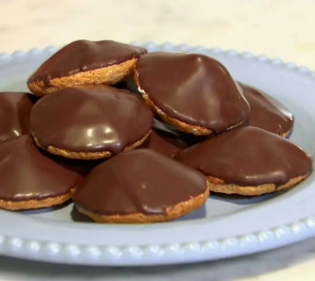 En hög med chokladöverdragna biskvier på en ljusblå tallrik. Perfekt för ett enkelt biskvier recept.