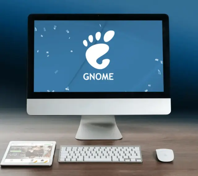 Komputer z logo GNOME, tablet i klawiatura na drewnianym biurku.