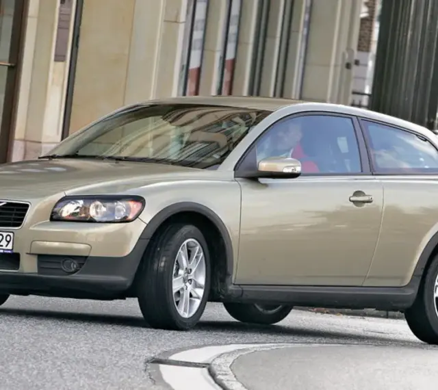 Złoty Volvo C30 z polskimi tablicami rejestracyjnymi WN 70829 jedzie po miejskiej ulicy.
