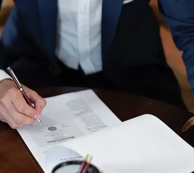Mężczyzna w garniturze podpisuje dokument, składając oświadczenie woli.