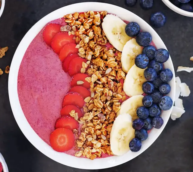 En färgglad acai bowl med jordgubbar, banan, blåbär och granola. Perfekt för en hälsosam frukost eller mellanmål.
