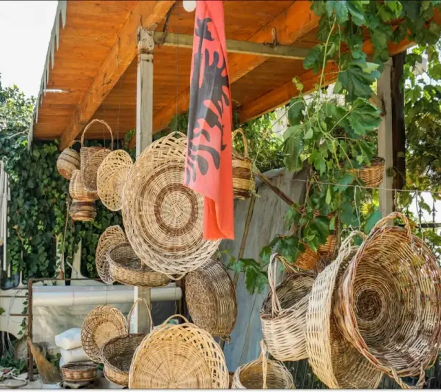 Wiele koszy z wikliny wisi pod zadaszeniem, obok albańskiej flagi. Czy Albania jest bezpieczna dla kobiet? Tak, to piękny kraj.