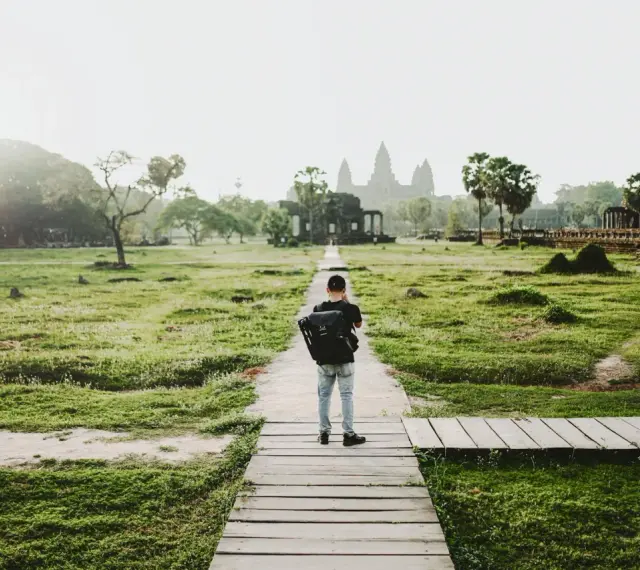 Chłopiec z plecakiem idzie ścieżką do Angkor Wat, jednego z cudów największego kontynentu na ziemi.