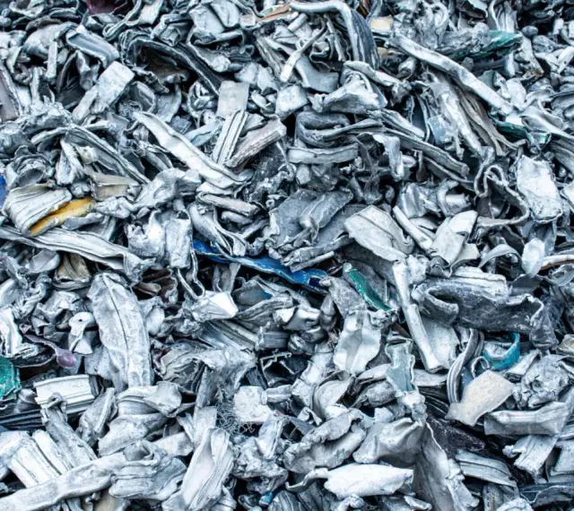 Góra poskręcanego, poszarpanego złomu metalowego, gotowego do recyklingu metalu. Widać fragmenty niebieskiego i żółtego plastiku.